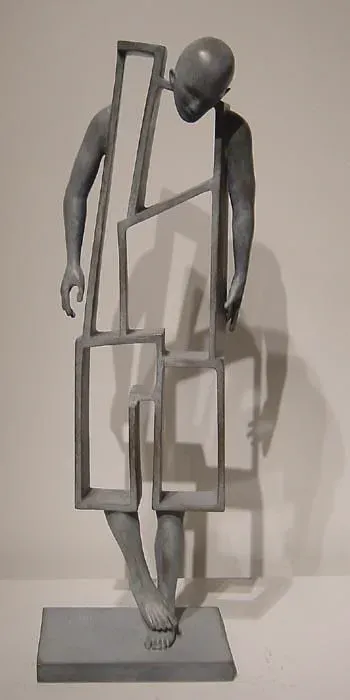 Scultura in bronzo patinato di una figura umana che porta cornici vuote incastrate lungo il corpo, proiettando un'ombra sulla parete chiara